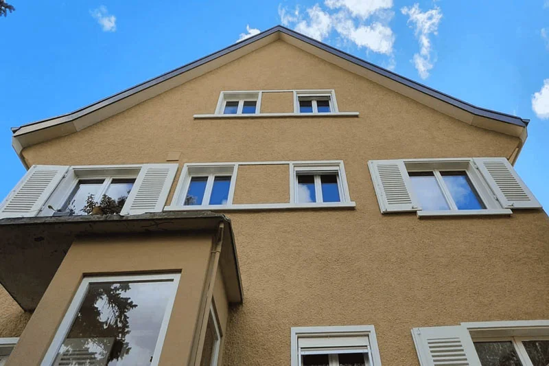 Aufnahme von unten von einem Haus. Das Haus sieht frisch saniert aus.
