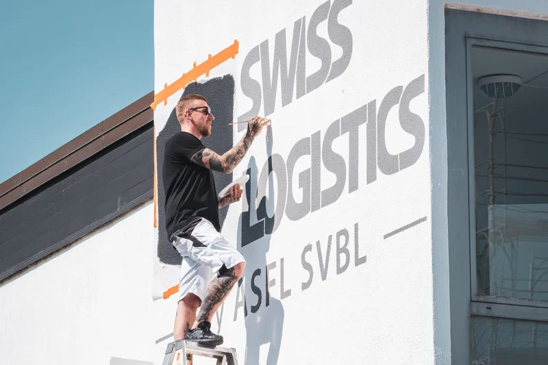 Maler bemalt eine Wand mit einem Unternehmenslogo