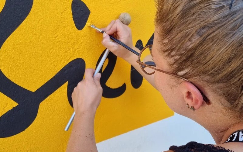 Kundenmalerin trägt Farbe für eine Beschriftung auf